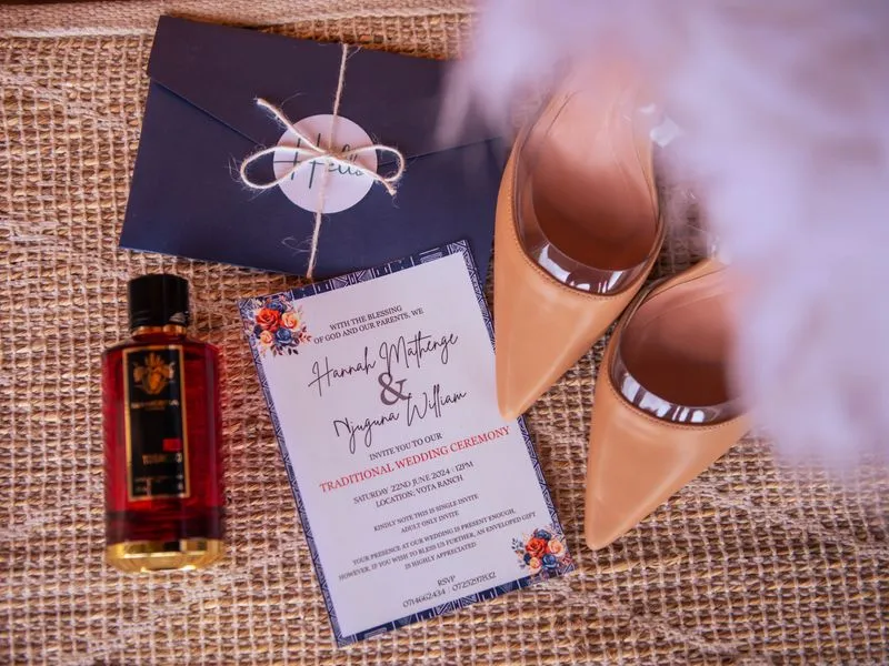 A printed wedding invitation next to a navy envelope and a pair of heels.